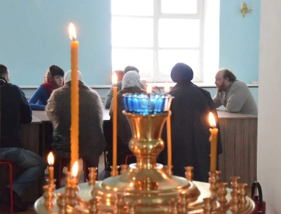 Священник и диакон совершают службу у аналоя с зажжёнными свечами