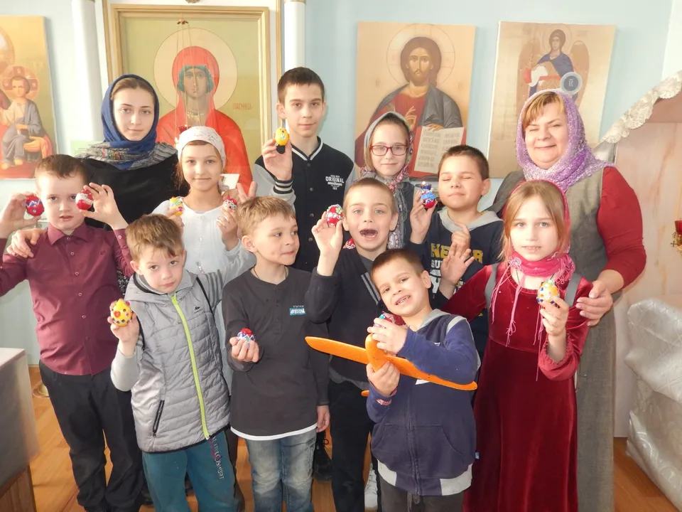 Дети и педагоги за столом с красками у пасхальных яиц