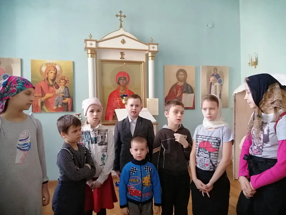 Дети стоят у аналоя рядом со священником