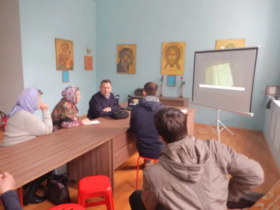 Слушатели за столами смотрят презентацию на экране