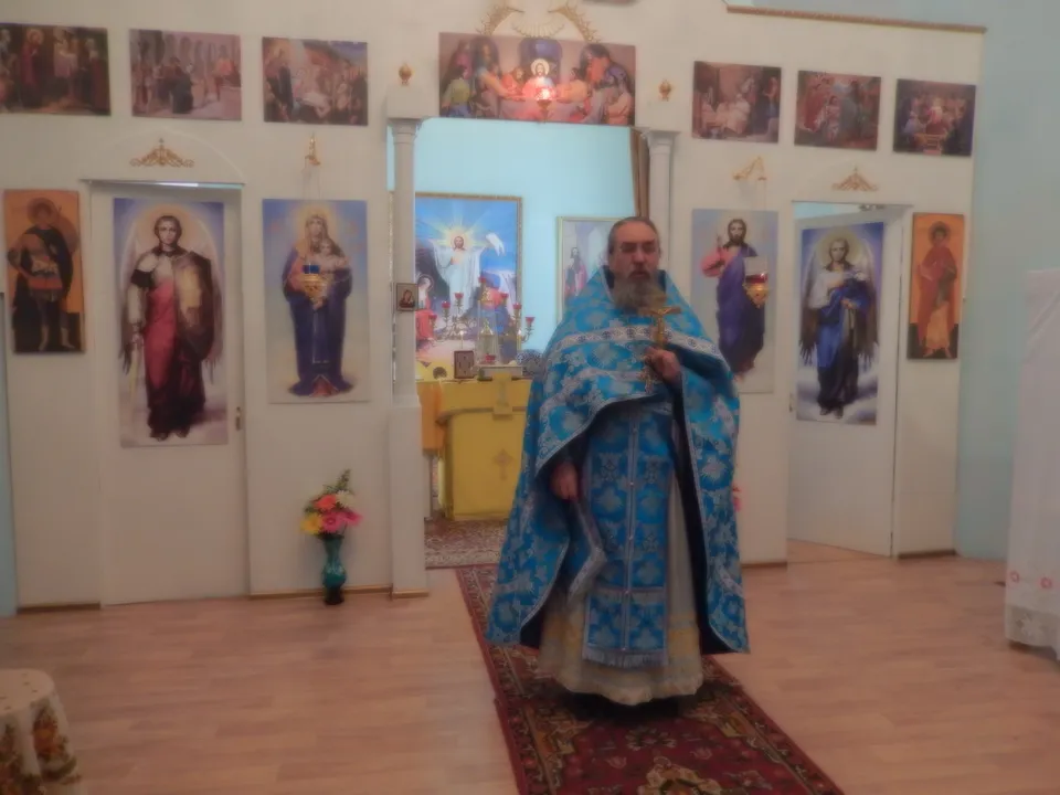 Священник в голубом облачении совершает молебен перед прихожанами