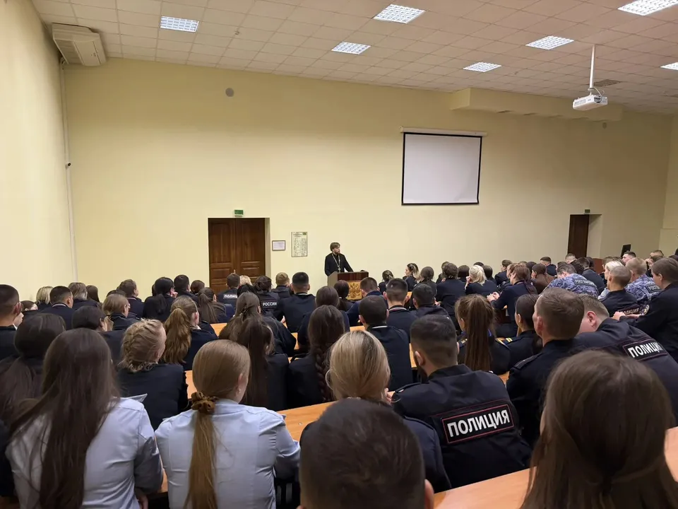 Священник обращается к слушателям, сидящим рядами в актовом зале